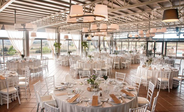 Sala de banquete de Masia Torreblanca con mesas redondas y ventanales al campo