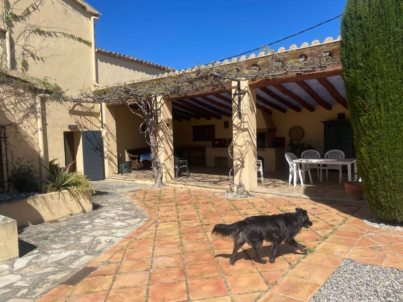 The covered porch at Cal Segue with tables and a barbecue, next to the tiled terrace