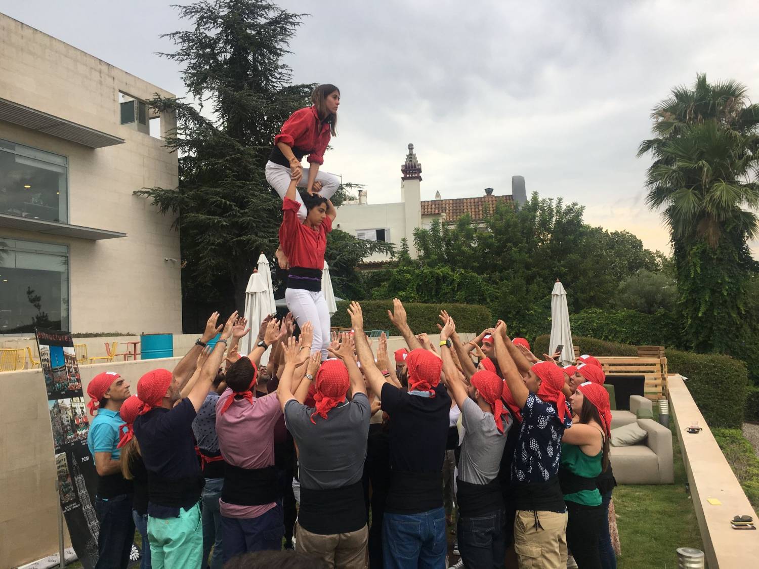 A company group raising a human tower at the «Fent Pinya» workshop, with casteller instructors in red shirts
